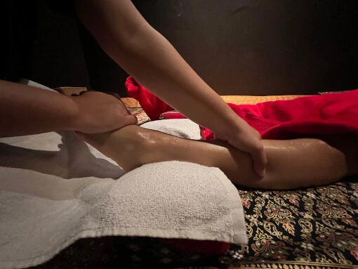 massage aux huiles d'un pied d'une dame couchée sur le dos. l'autre jambe est recouverte d'une serviette.