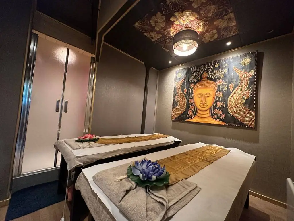Salle pour massage en duo avec une douche privative. Des décoration murales à l'effigie de Boudha sont aussi présentes.